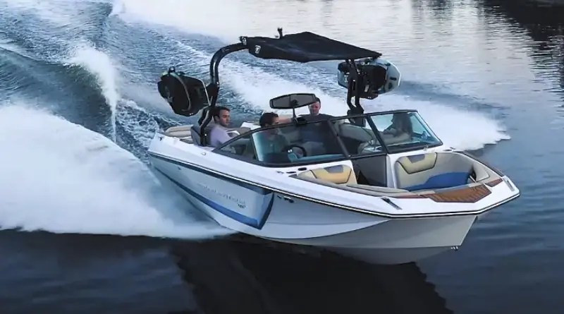 Nautique all-electric ski boat speeding along a lake with a wakeboarder in tow