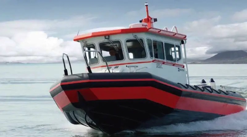 A red work boat goes through icy waters