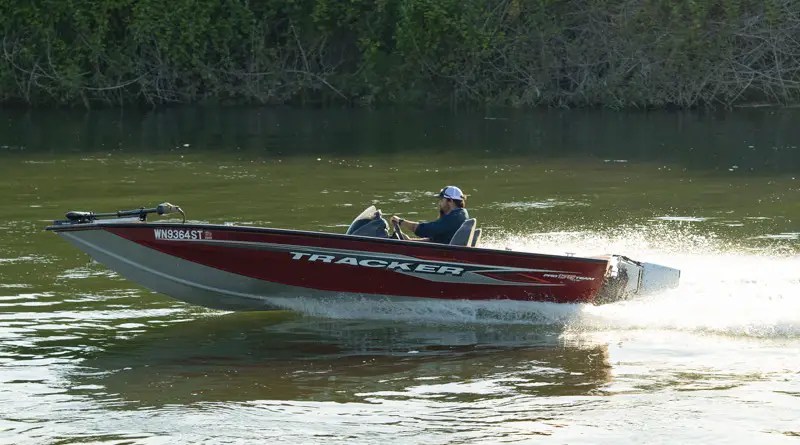 one of the electric boat packages is this fishing boat shown speeding along a river