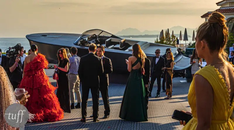 Guests at an elegant AIDS research cocktail party at Cannes gather around a beautiful 10m electric yacht up for auction